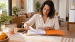 gestão de documentos da empregada doméstica: Mulher em casa revisando papéis e organizando documentos sobre a mesa, com caneta e celular ao lado, preparando arquivos para gestão de rotina